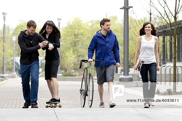 A group of friends having fun with a bike and a skateboard in the city.