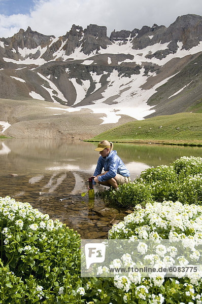 A woman filtering water from Blue Lake  Uncompahgre National Forest  Colorado.