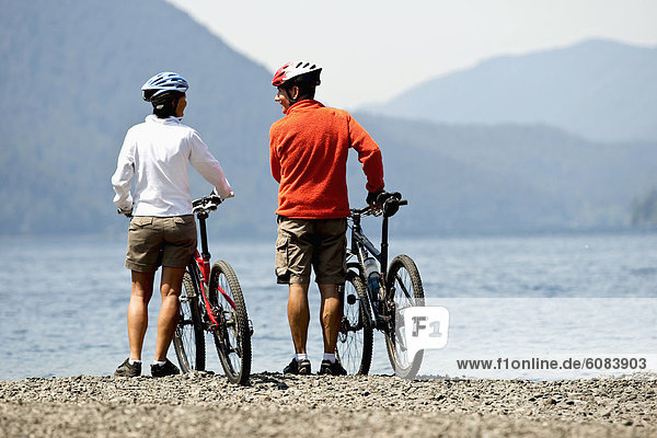 Mountain bikers enjoying views of the lake and hillsides covered in trees.