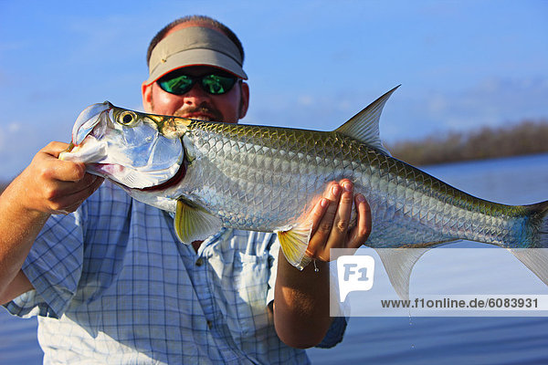 A fly fisherman with a small tarpon that caught with a fly rod on Great Inagua in the Bahamas.