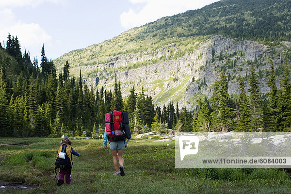 Mother and daughter backpacking through a meadow in a wilderness area.