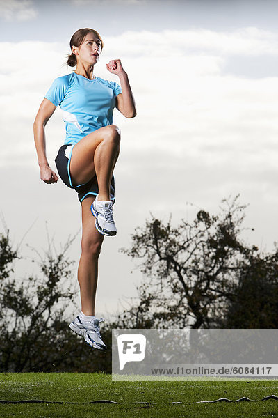 An athletic woman jumping in the air to prepare for a run in San Diego  California.