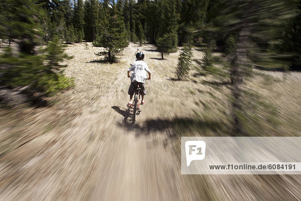 A young boy mountain bikes on a trail through the Eastern Sierra Mountains. (motion blur)