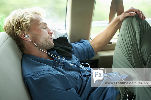 A man uses earphones and naps while traveling in Florida.
