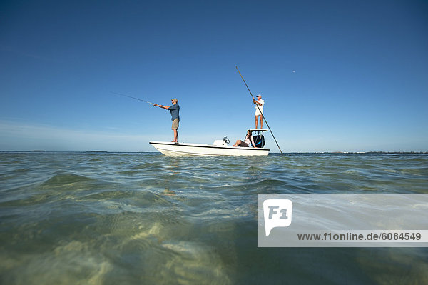 A couple fish as a man pilots a small boat in Florida.