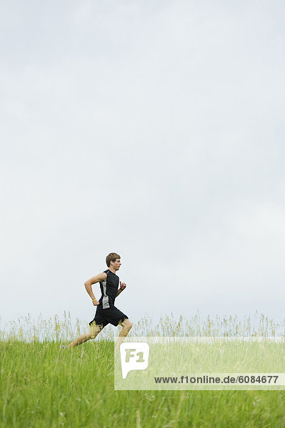 Young man running on a grass trail through a bright green field at Spirit Mound  South Dakota.