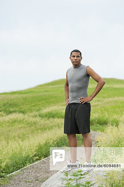 Young man standing on rock after running on gravel trail through a bright green field at Spirit Mound  South Dakota.