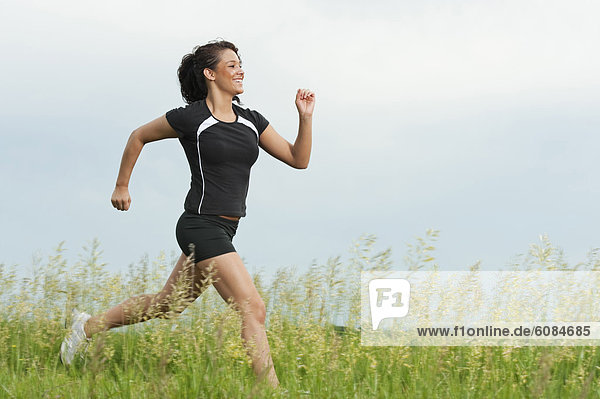 Young woman running on grass trail through a bright green field at Spirit Mound  South Dakota.