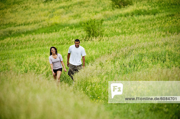 Young couple walking on a grass trail through a bright green field at Spirit Mound  South Dakota.