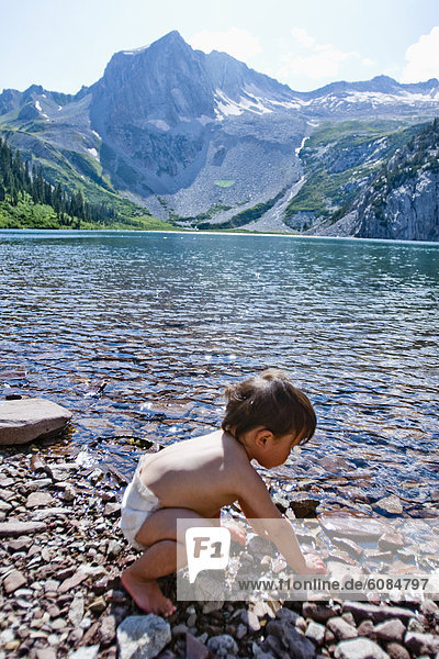 A 14 month boy plays in the waters of Snowmass Lake (10 980ft) with Snowmass Mountains in the background.