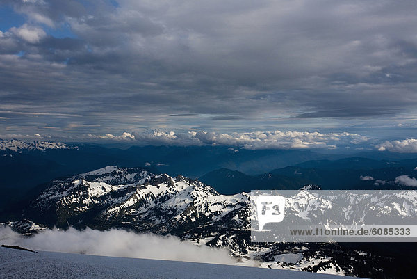 A landscape image of snow capped Mount Rainier in the Cascades at dusk.