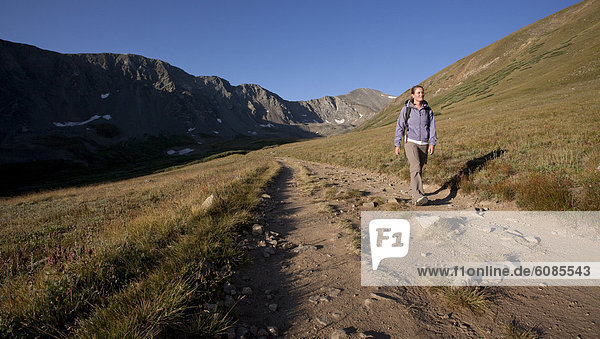 A woman hikes down from Grey's Peak in the early morning sun of the Colorado Mountains.