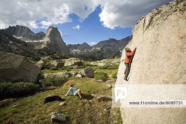 A male climber boulders in the Cirque of the Towers while his wife and dog look on  Wind River Range  Wyoming.