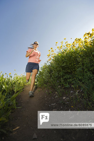 A young woman trail runs amongst wild flowers.