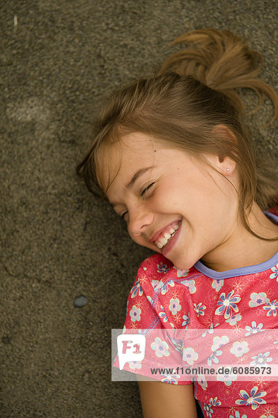A young girl giggles while lying in the sand  Dunganess Spit  Straight of Juan del Fucca  Washington.
