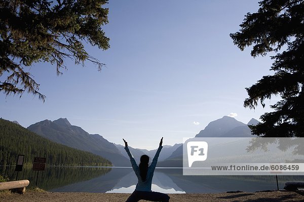 Silhouette of a woman practicing outdoor yoga at a remote lake in Glacier National Park.