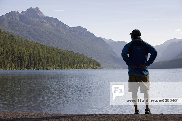 Man looking over a remote lake and mountains deep in Glacier National Park.