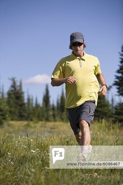 Man running through grass while hiking high in the Rocky Mountains.