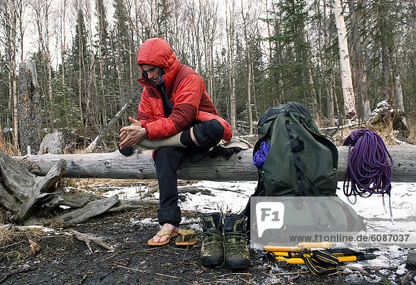 A young man warms his feet with socks during a winter camping trip in Anchorage  Alaska.