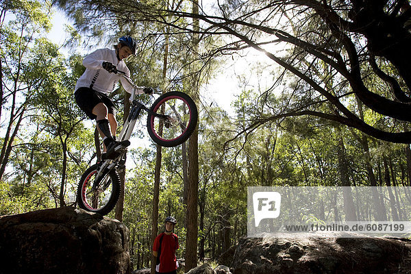 A Trials rider prepares to leap off a rock at Toohey Forest  Brisbane  Queensland  Australia.