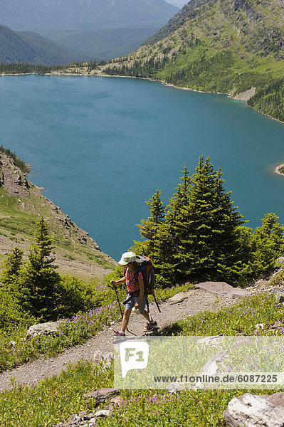 A young girl hikes a trail overlooking a alpine lake in Glacier National Park  Montana.