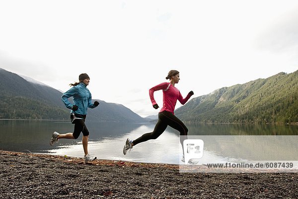 Two females jogging together along the shore of Lake Crescent.