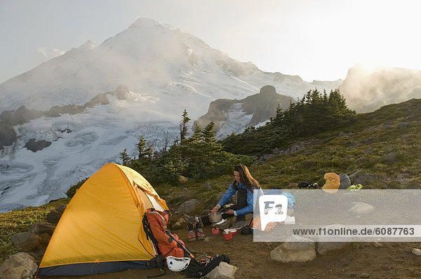 A woman cooking a meal while camping below Mount Baker  Mount Baker Wilderness  Bellingham  Washington.