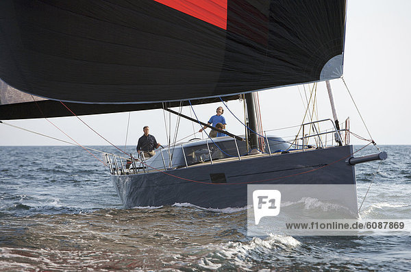 A crew races a modern ocean-going sailing yacht under spinnaker.