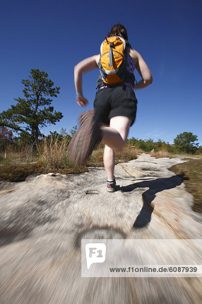 Blur motion of woman running on a rocky trail in North Carolina.