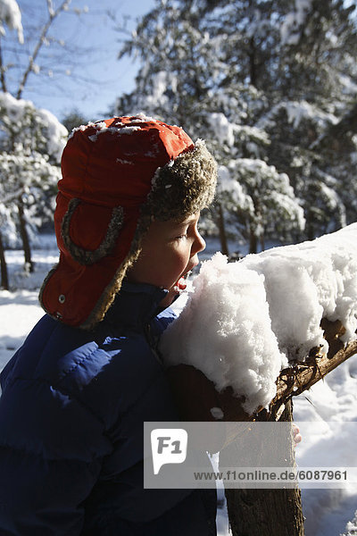 Junge - Person  Hut  essen  essend  isst  jung  Geländer  Schnee