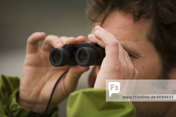 A man uses binoculars on The Lost Coast  California.