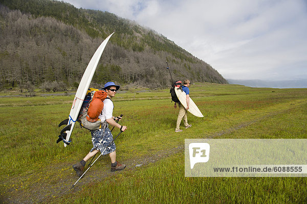 Two men hike with surfboards on The Lost Coast  California.