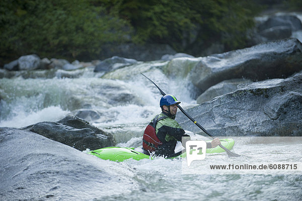 A whitewater kayaker sits in an eddy after running a series of rocky drops.