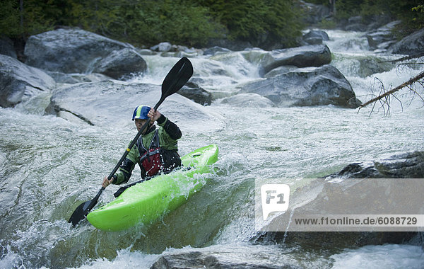 A whitewater kayaker continues down a rocky section of a high moutain river.