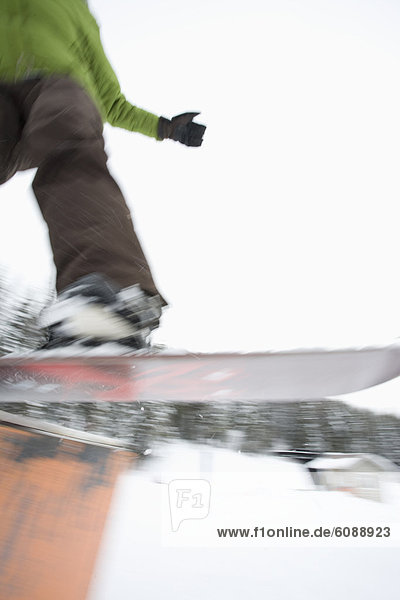 Blur of a snowboarder getting air off a ski park jump