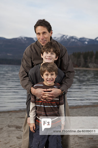 A family takes a portrait on the beach of an alpine lake.
