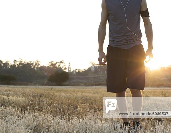 Male runner stays still for a portrait at an open field with backlight in San Diego  California.