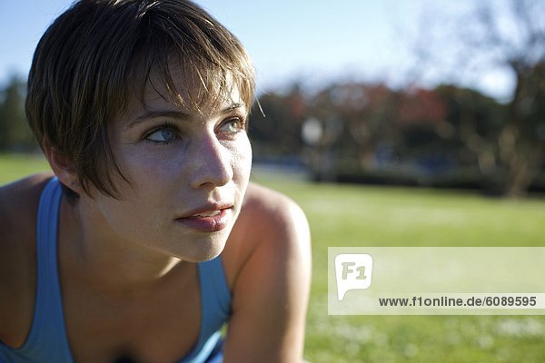 Woman wearing workout shirt looks away from the camera at a park in Coronado  California.