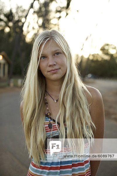 A pre-teen girl with long blond hair poses for the camera in Maui  Hawaii on an early morning at Paia Beach.