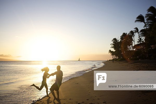 Happy  young couple dance and play at the beach right before sunset in Maui  Hawaii.