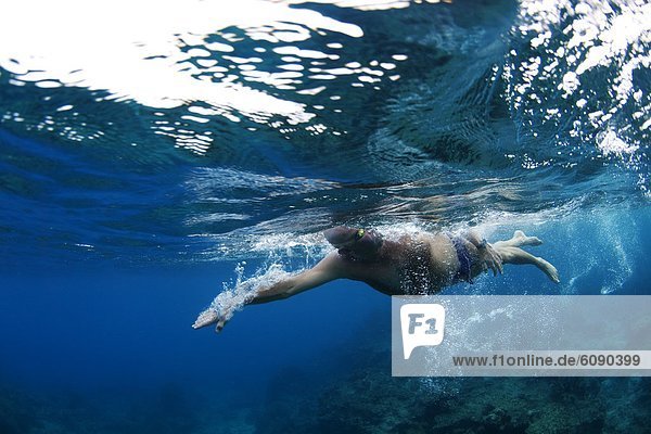 Underwater view of a swimmer enjoying a relaxing swim in the tropical waters off of Mana Island  Fiji.