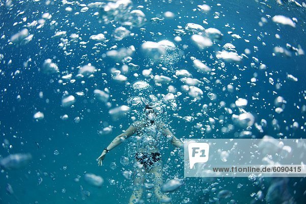 Underwater view of a swimmer behind a wall of bubbles in the tropical waters off of Mana Island  Fiji.