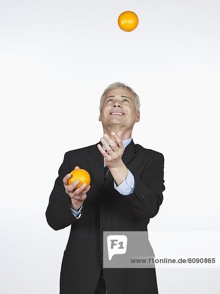 Mature man juggling with oranges