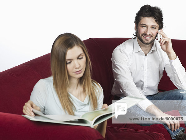 Frau liest Buch  Mann benutzt Handy im Hintergrund