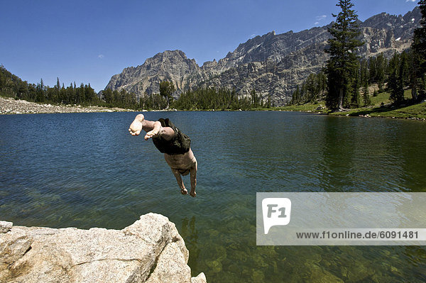 A young man jumps into a lake in Grand Teton National Park.