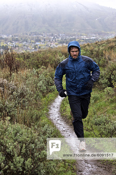 A man runs during a snow and rain storm for excercise.