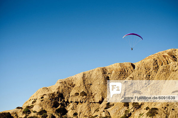 A hang glider floats above the cliffs of Torrey Pines over La Jolla  California.