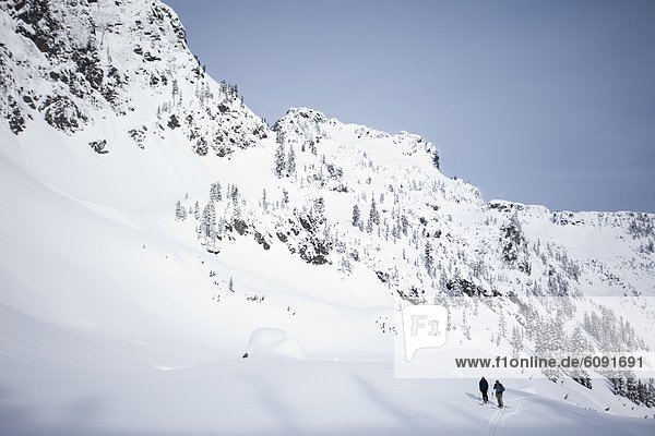 Two skiers in the backcountry on a clear day.