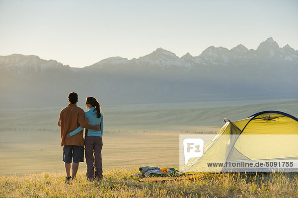 A young couple enjoy the last rays of the day while camping.