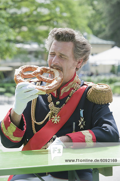 Germany  Man as King Ludwig of Bavaria eating pretzel